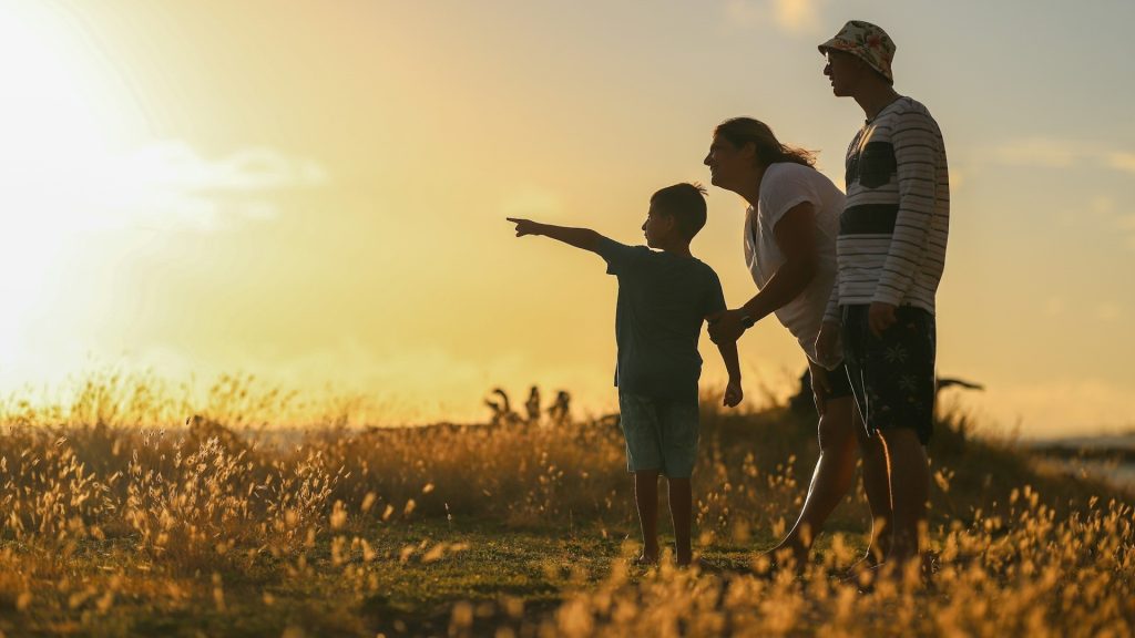 Family walking in a field at sunset